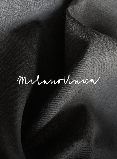Folds of dark grey wool fabric with the handwritten-style white logo "Milanollnica" across the center