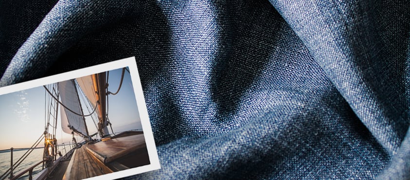 Draped blue woven fabric with a small photo of a sailboat's wooden deck and sails at sunset