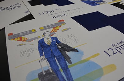 Printed card with illustration of a man in a blue suit with luggage, beside navy Reda fabric swatches