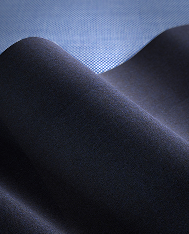 Close-up of dark navy wool fabric folded in soft waves over a light blue finely woven textile