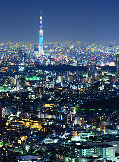 Tokyo Skytree lit in blue above the glowing city skyline at night