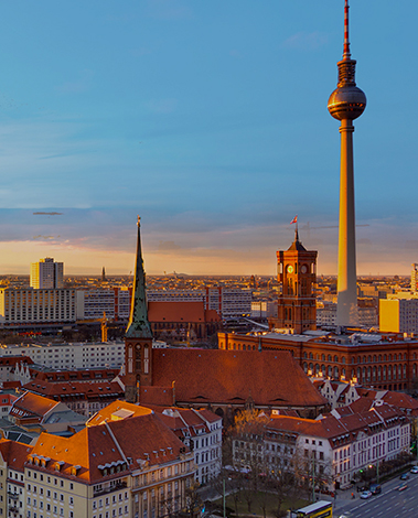 Berlin skyline at sunset with the TV Tower, Red Town Hall and a church spire above red-roofed buildings