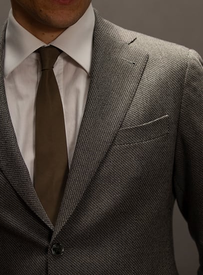 Close-up of a man in a textured gray wool jacket, white shirt and olive-brown knit tie