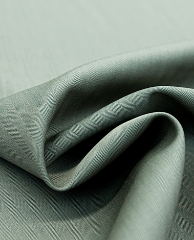 Close-up of sage green herringbone fabric folded into soft curves