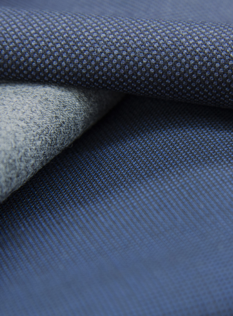 Close-up of folded blue and grey wool fabrics with micro-dot and fine ribbed textures