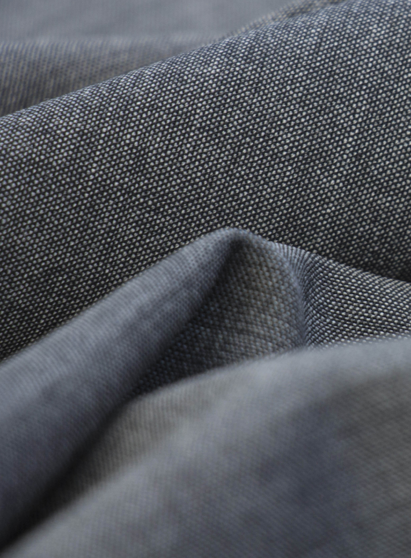 Close-up of grey-blue woven fabric with a fine textured weave, softly draped in folds