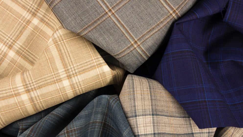 Folded plaid wool fabrics in beige, gray, navy blue and blue-gray, arranged together