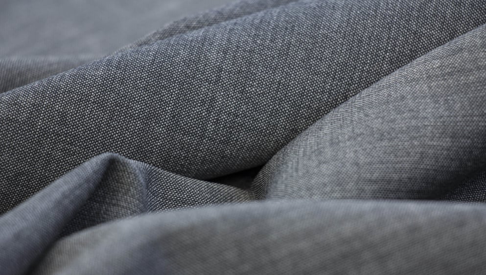 Close-up of grey woven fabric with a fine texture, draped in soft folds