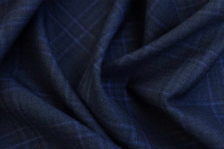 Close-up of draped navy blue wool fabric with a subtle light blue check pattern