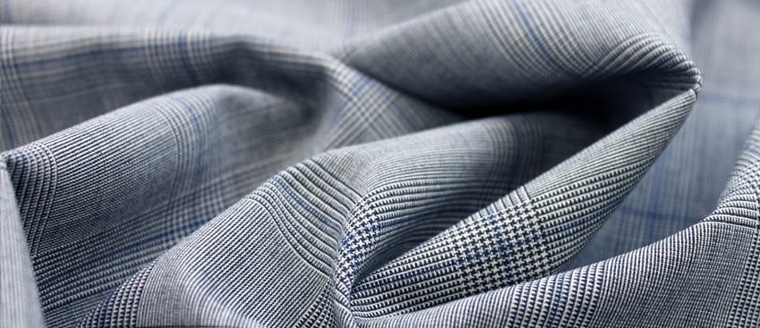 Close-up of draped gray-blue Glen check fabric with a fine houndstooth weave and blue overcheck