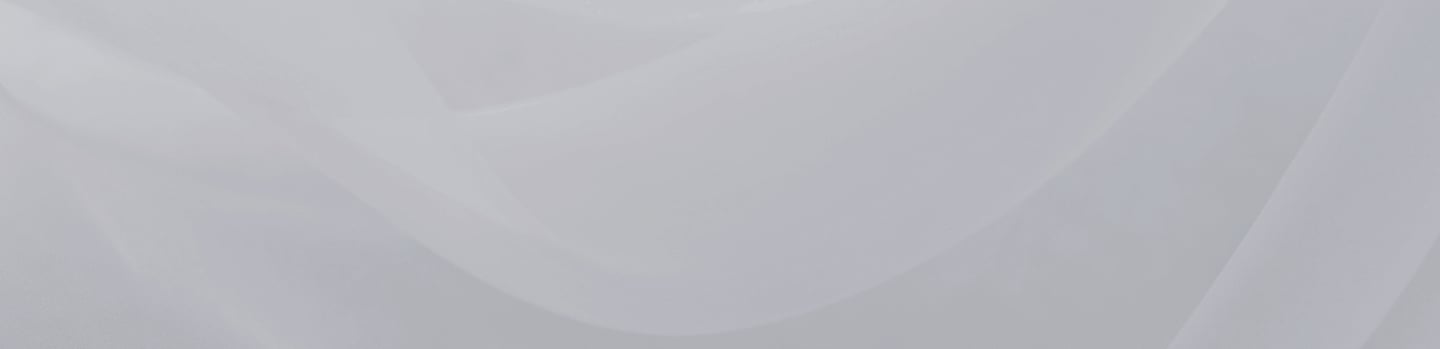 Soft, translucent gray fabric folds forming gentle overlapping waves on a pale background