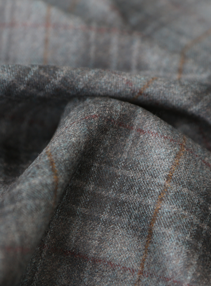 Close-up of draped gray wool fabric with a thin orange and red windowpane check pattern